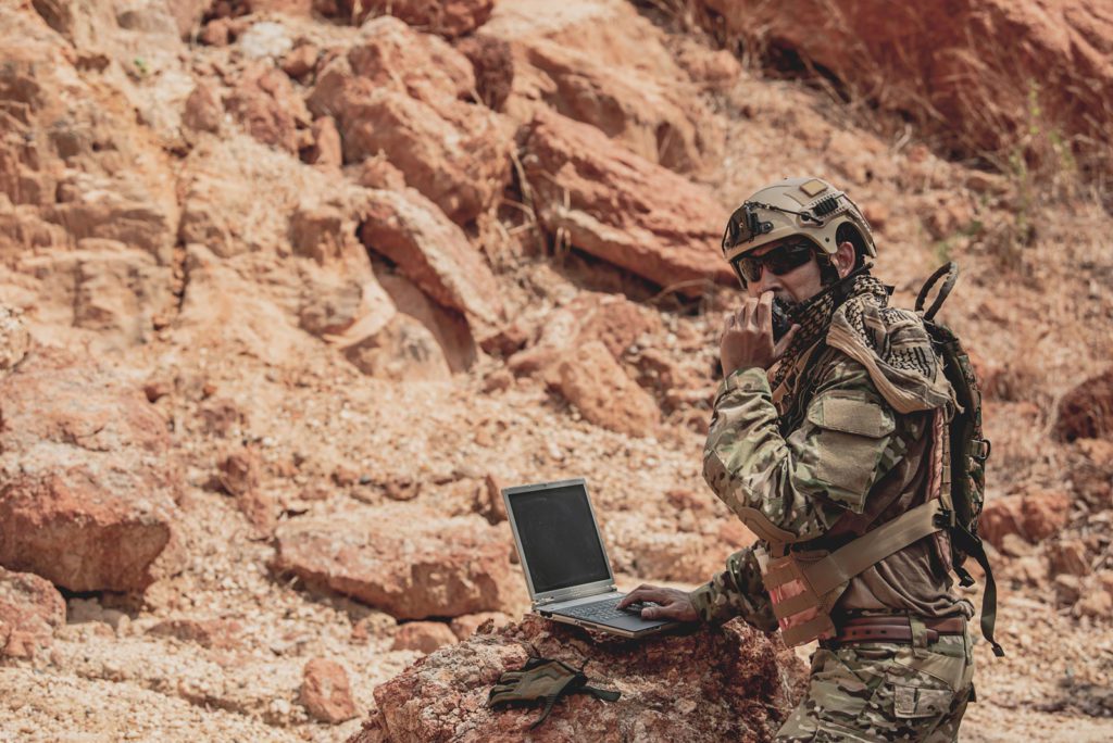 Soldier With Radio And Laptop In Desert